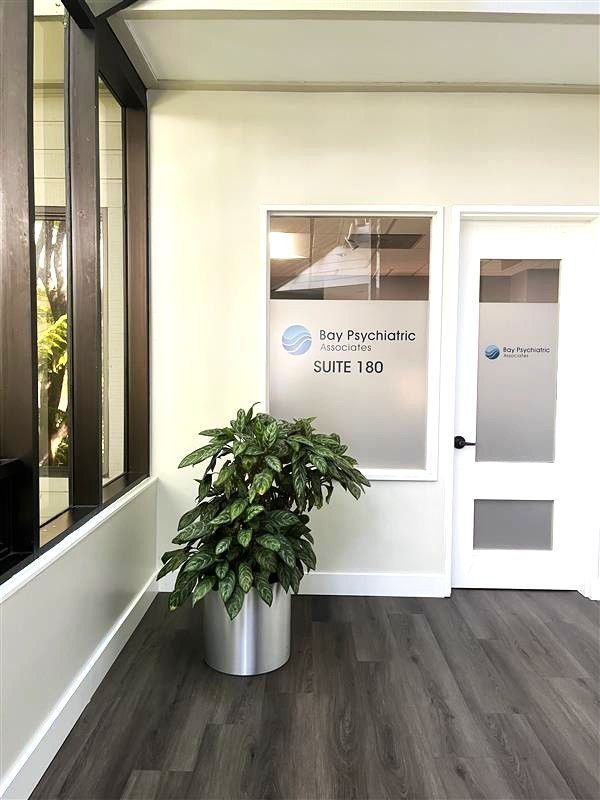 Corte Madera clinic entrance with Bay Psychiatric Associates Suite 180 signage and a potted plant.