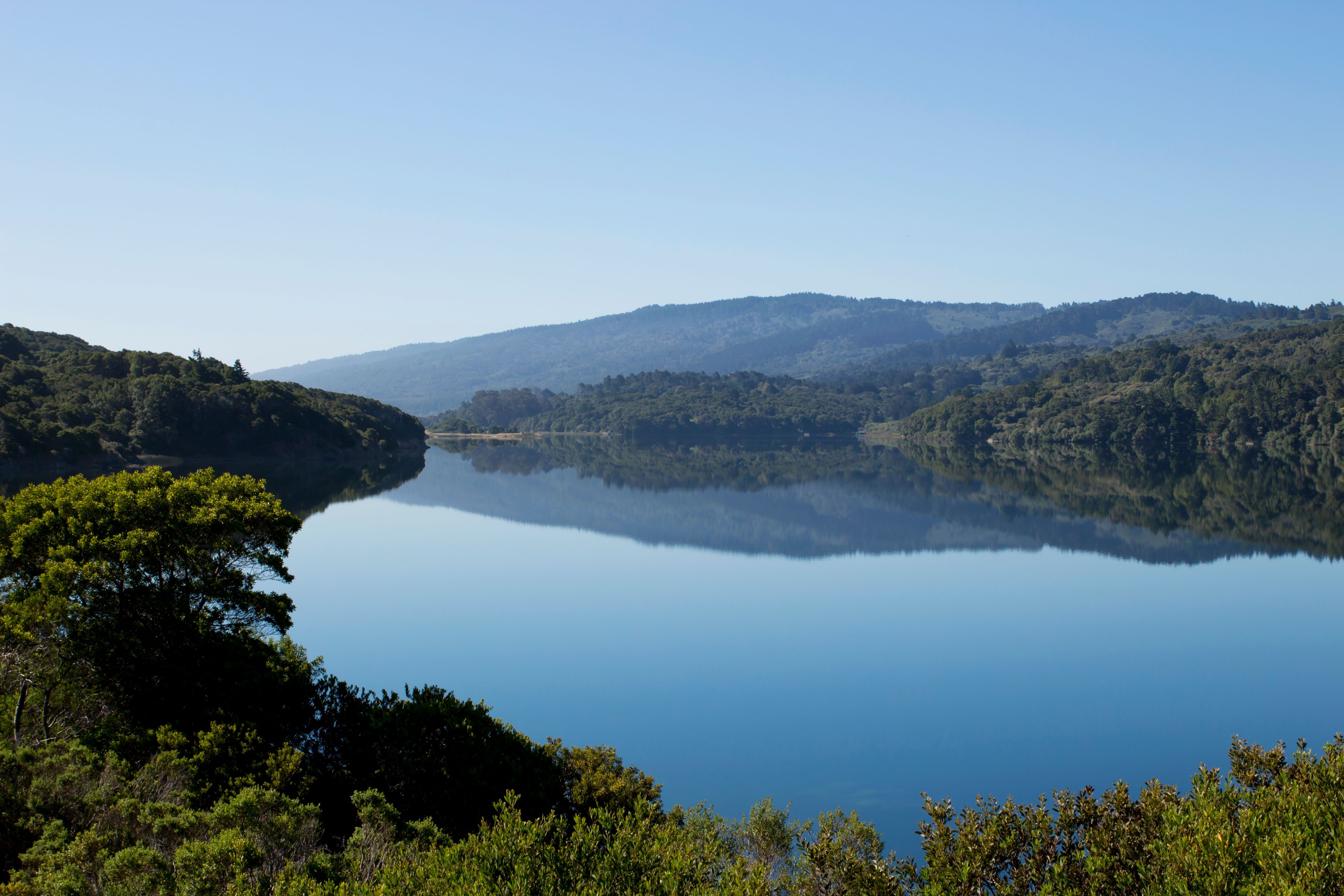 Blue water at Crystal Springs Reservoir reflecting wooded Peninsula hills.